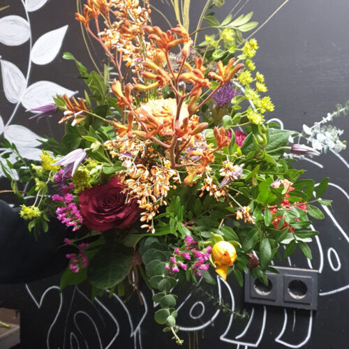 Boeket met roze-rode bloemen en oranje takjes